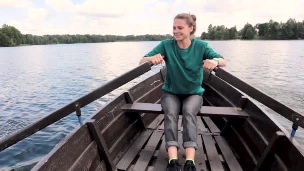 Uma jovem mulher bonita está navegando em um barco no lago . — Vídeo de Stock