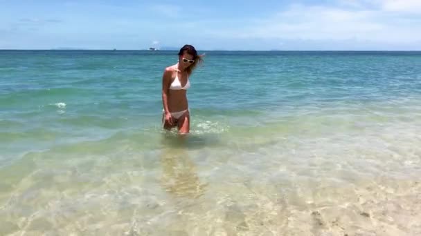 穿着比基尼的年轻漂亮女人从海边的热带海滩上走出去 — 图库视频影像