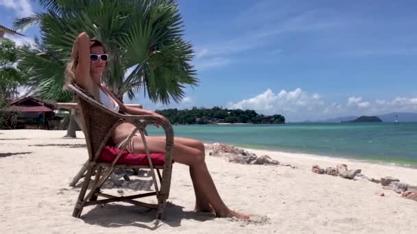 Νεαρή Όμορφη Γυναίκα Κάθεται Στην Καρέκλα Στην Τροπική Παραλία Μπικίνι — Αρχείο Βίντεο