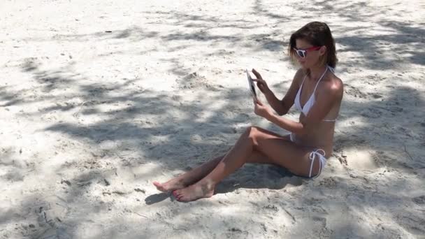 坐在沙滩上的年轻女子手里拿着一块药片 — 图库视频影像