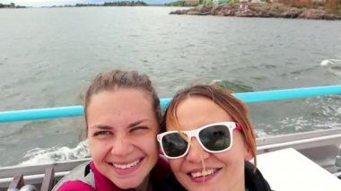 4k video. Genç bir lezbiyen çift Finlandiya'da bir gemide yelken ve bir selfie alarak. Yanağından öpmek.