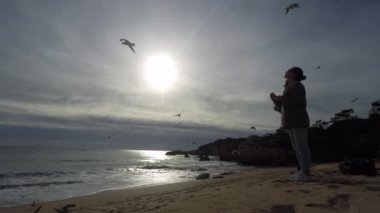 İki genç kadın bir sürü martı okyanus sahilde duran yem.