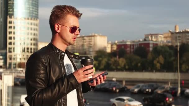 Een Stijlvolle Jonge Man Zonnebril Staat Straat Met Een Smartphone — Stockvideo