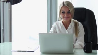 Onun ofisinde oturan bilgisayarda çalışan genç yakışıklı iş kadını.