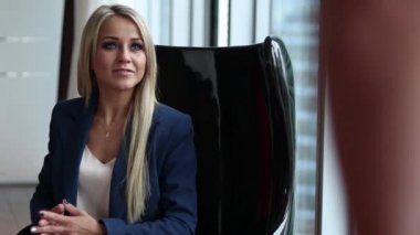 Bir ofiste bir sandalyede oturan genç güzel kadın personel Yöneticisi. Röportaj.