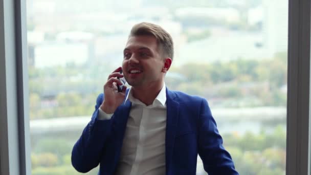 Молодий Красивий Чоловік Розмовляє Телефону Стоячи Біля Вікна Офісі — стокове відео