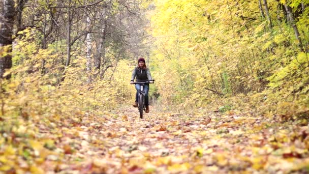 若い女性は 秋の森で自転車に乗っています 月気分 — ストック動画