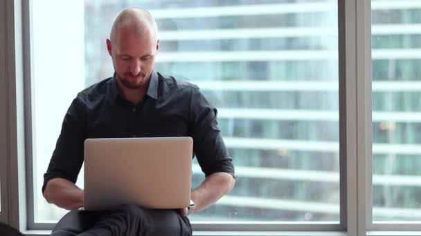 Jovem empresário está sentado no chão do escritório com um laptop . — Vídeo de Stock