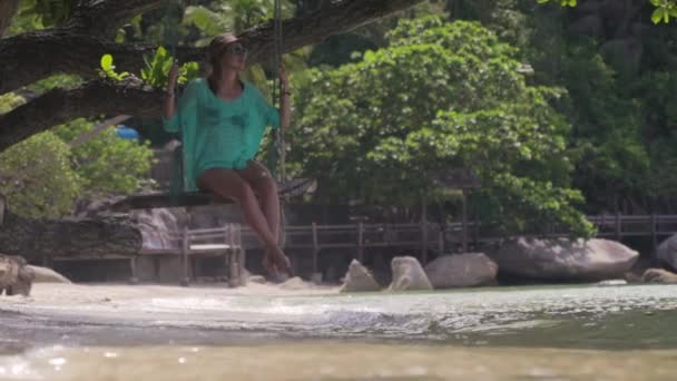 Молодая женщина качается на качелях на пляже на тропическом острове . — стоковое видео