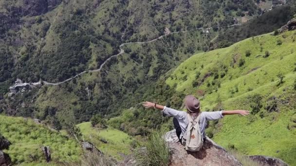 Woman traveler is sitting on the big rock in the mountain. — Stock Video