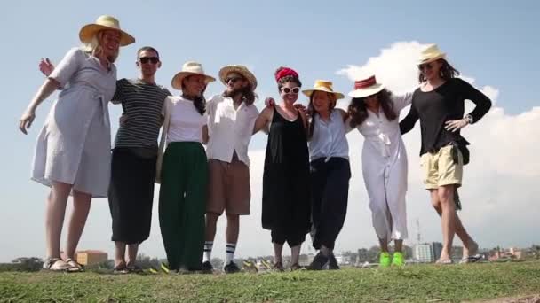 Een groep jonge mensen die poseren voor de fotograaf op de achtergrond van een hemel. — Stockvideo