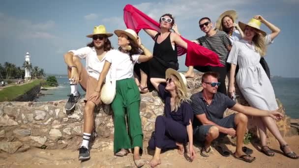 Большая Группа Счастливых Друзей Сидит Каменном Заборе Видом Знаменитый Маяк — стоковое видео