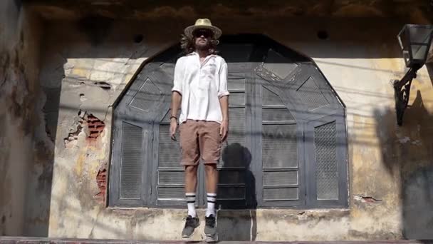 一个戴着草帽和太阳镜的年轻人一遍又一遍地跳着 循环素材 有趣的Gif动画跳人 — 图库视频影像