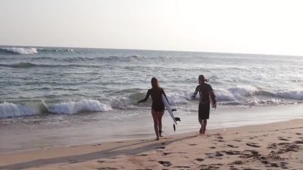 Een jong paar surfers rennen naar de oceaan met surfplanken — Stockvideo