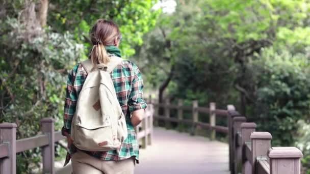 Молодая Женщина Рюкзаком Гуляет Весеннему Парку Наслаждается Видом Деревянный Мост — стоковое видео