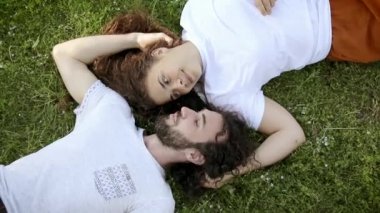 Güzel kıvırcık sevgi dolu çift parkta çim üzerinde yatan, romantik an.