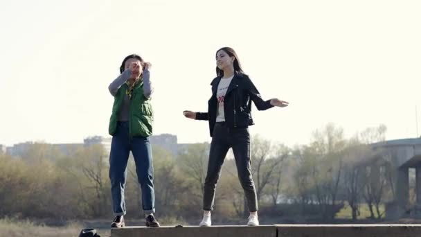Duas meninas adolescentes asiáticas bonitas felizes estão dançando na rua . — Vídeo de Stock