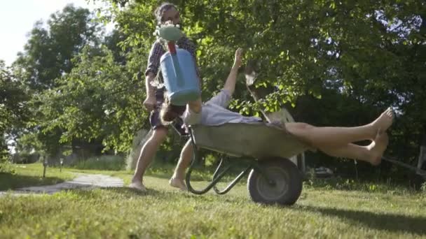 Joven pareja feliz divirtiéndose y montando un carro de campo . — Vídeos de Stock