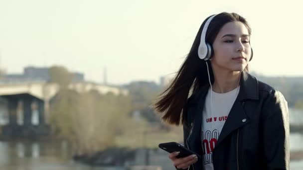 Asijská dívka s brunetou, která poslouchala hudbu se sluchátky — Stock video