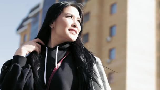 Όμορφο νεαρό κορίτσι της Ασίας με μακριά μαύρα μαλλιά στέκεται στο δρόμο — Αρχείο Βίντεο