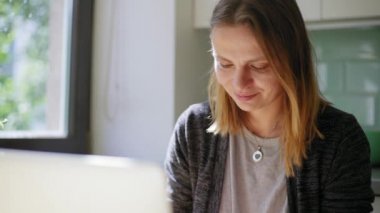 Genç kadın serbest bir dizüstü bilgisayarda e-posta yazarak evden serbest çalışan