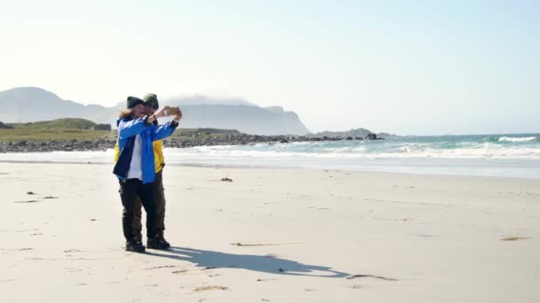 Δύο νεαρές γυναίκες ταξιδιώτες παίρνουν μια selfie με ένα smartphone στην παραλία — Αρχείο Βίντεο