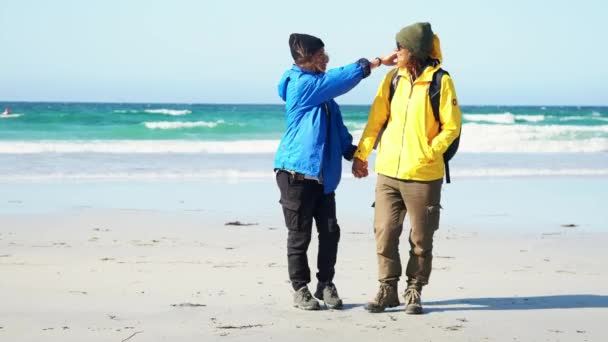 Dwie młode kobiety chodzą w kierunku kamery i trzymając ręce na plaży — Wideo stockowe