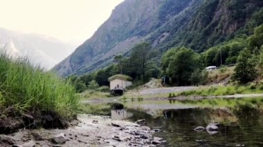 Sinematik görüntüler. Arka planda küçük ev, göl ve dağlar ile tipik Norveç manzara.