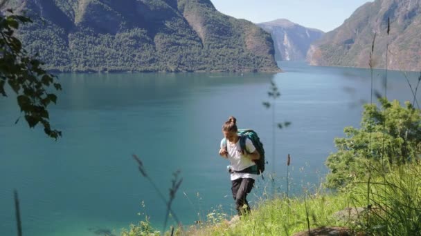 Mujer joven con una gran mochila caminando al borde de la colina — Vídeos de Stock