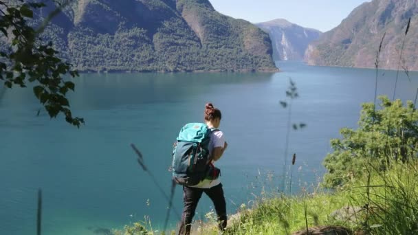 Jeune femme avec un grand sac à dos marchant au bord de la colline — Video