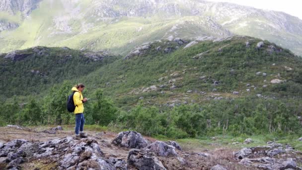 Szczęśliwa kobieta Backpacker stoi na wzgórzu i za pomocą smartfona. — Wideo stockowe