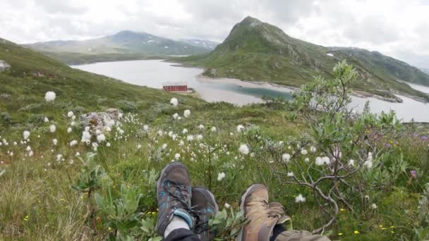 Két utazó ül a dombon egy norvég fjord felett.. — Stock videók