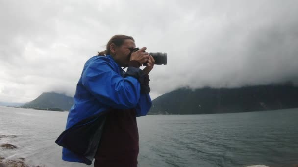 Vrouw professionele fotograaf het nemen van foto 's van een stormachtige Noorse landschap. — Stockvideo