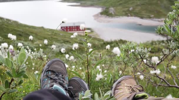 Two travelers sitting on the hill above a Norwegian fjord. — Stock Video