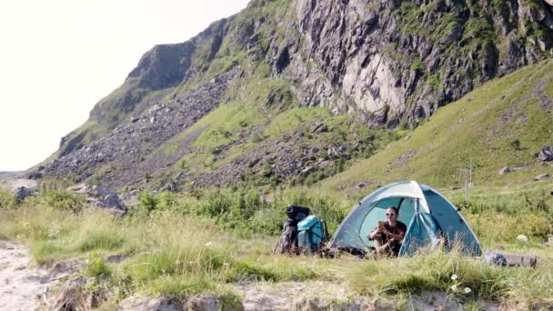 A young woman traveler sitting inside her tourist tent and using her smartphone. — Stock Video