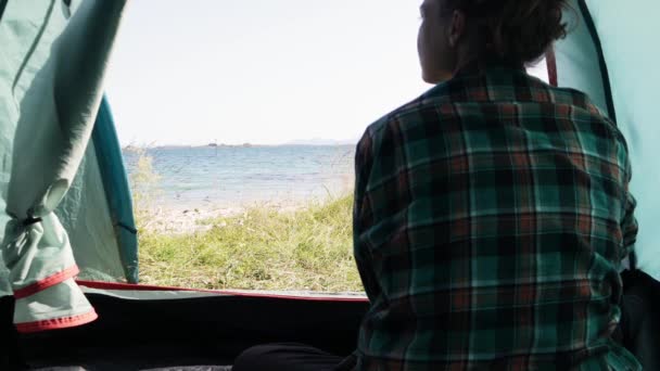 Mladá žena cestovatel sedí uvnitř svého turistického stanu. — Stock video