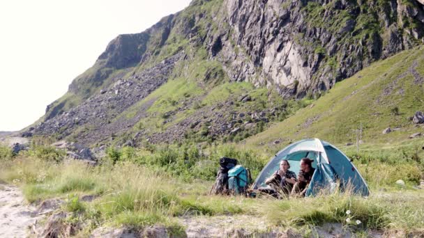 Two young woman travellers sitting inside a tent and enjoying a morning coffee — Stock Video