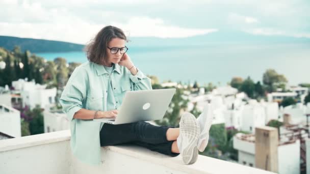 Mladá žena na volné noze pracuje se svým notebookem na terase střechy. — Stock video