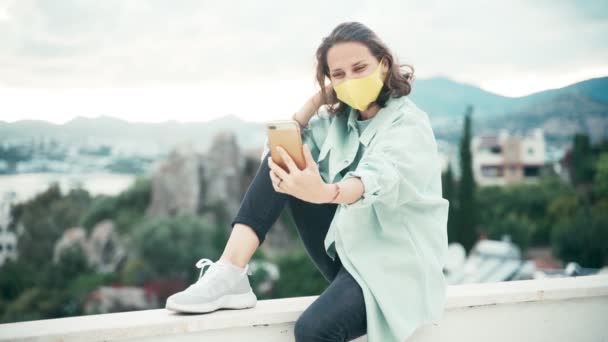 Jeune femme en masque jaune enregistrement vidéo pour les médias sociaux avec son smartphone — Video