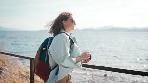 Feliz joven mujer toma una foto en una cámara de fotos caminando mar, viajes de verano — Vídeo de stock