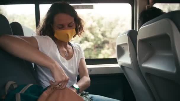 Νεαρή γυναίκα με προστατευτική μάσκα σε λεωφορείο μαζικής μεταφοράς με smartphone — Αρχείο Βίντεο