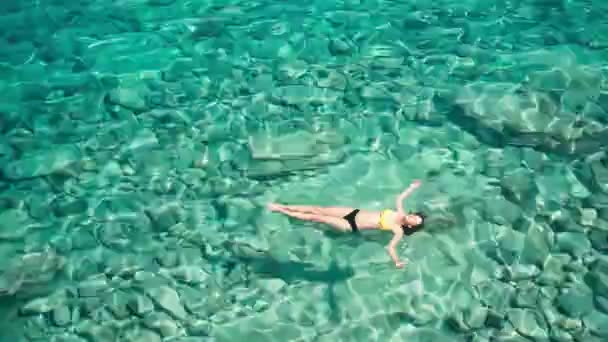 Körfezde mavi deniz suyunda yüzen bir kadın. Doğa ve rahatlama, üst görünüm — Stok video