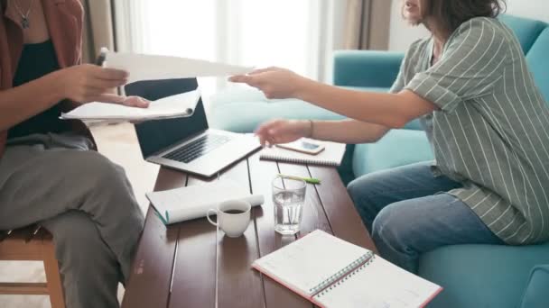 Primer plano de dos mujeres jóvenes discuten un proyecto de negocios en casa en el sofá — Vídeo de stock