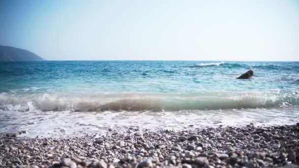 Filmbeelden van een leeg kiezelstrand met kristalheldere blauwe golven — Stockvideo