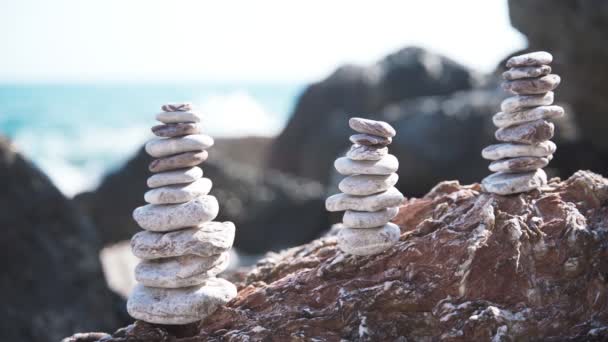 Tres pirámides equilibradas de piedras en la playa en el fondo de las olas del mar — Vídeos de Stock