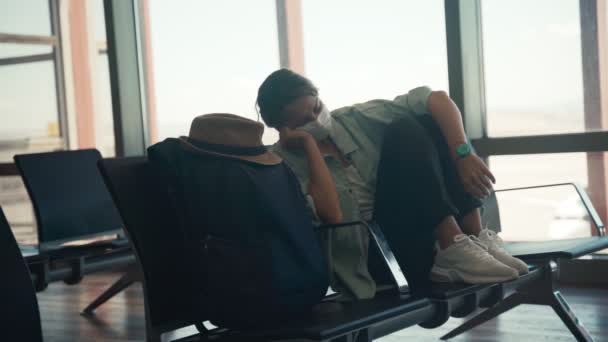 Una joven con una máscara protectora durmiendo en el salón del aeropuerto — Vídeo de stock