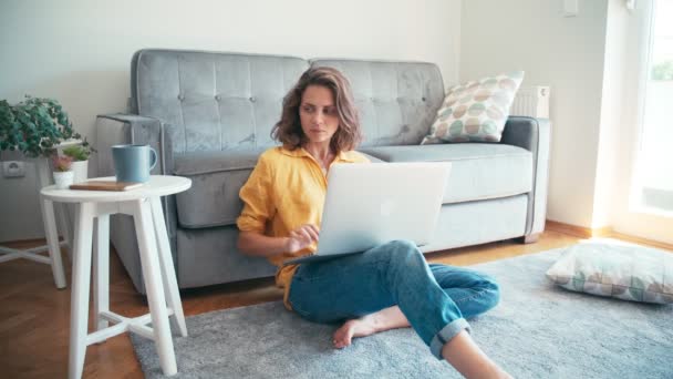 Jeune femme sérieuse employée à distance travaillant sur son ordinateur portable à la maison — Video