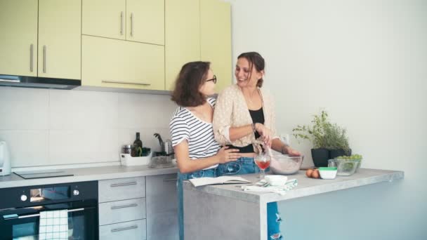 Pareja lesbiana bailando y bebiendo vino mientras cocinan juntos — Vídeo de stock