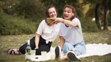 İki genç, neşeli kadın akıllı telefonuyla selfie çekiyor.