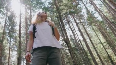 Genç bir kadının yaz ormanında sırt çantalı fotoğrafı.